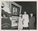 Three people in front of a parade truck