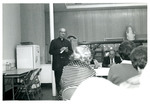 Priest addresses a group of people seated at tables